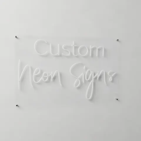 The same neon sign switched off on a light wall: milky white tubes on a clear acrylic board