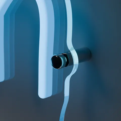 Stainless steel standoff holding the clear acrylic board of a lit neon sign off the wall