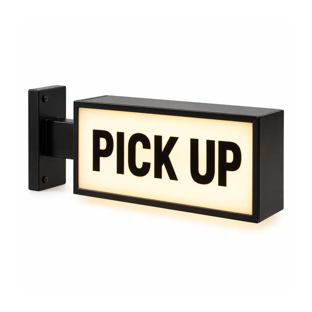 PICK UP light box sign: black letters on a lit warm white face in a black frame, on a right-angle wall bracket, on a white background