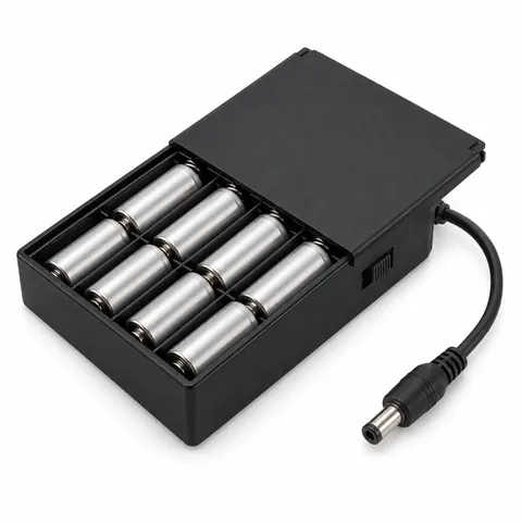 Black battery box holding eight AA batteries, lid slightly open, with a slide switch and a DC barrel plug cable, on a white background