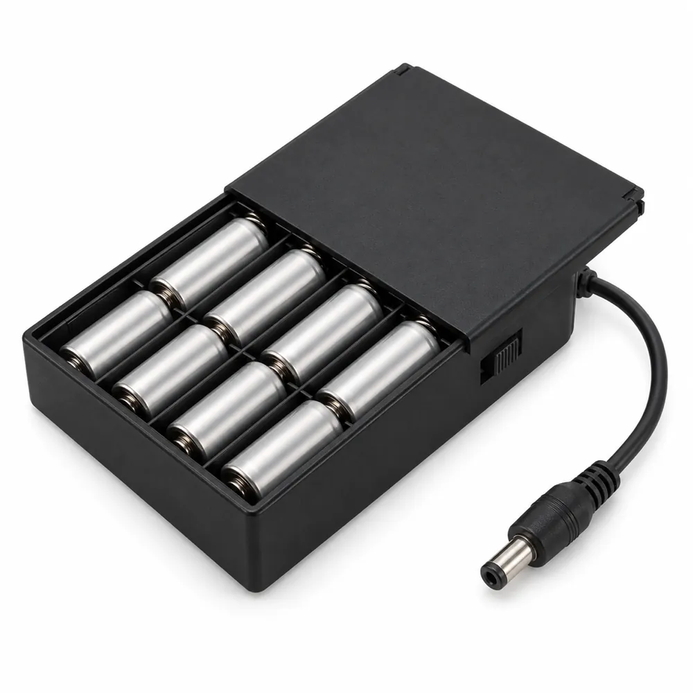 Black battery box holding eight AA batteries, lid slightly open, with a slide switch and a DC barrel plug cable, on a white background